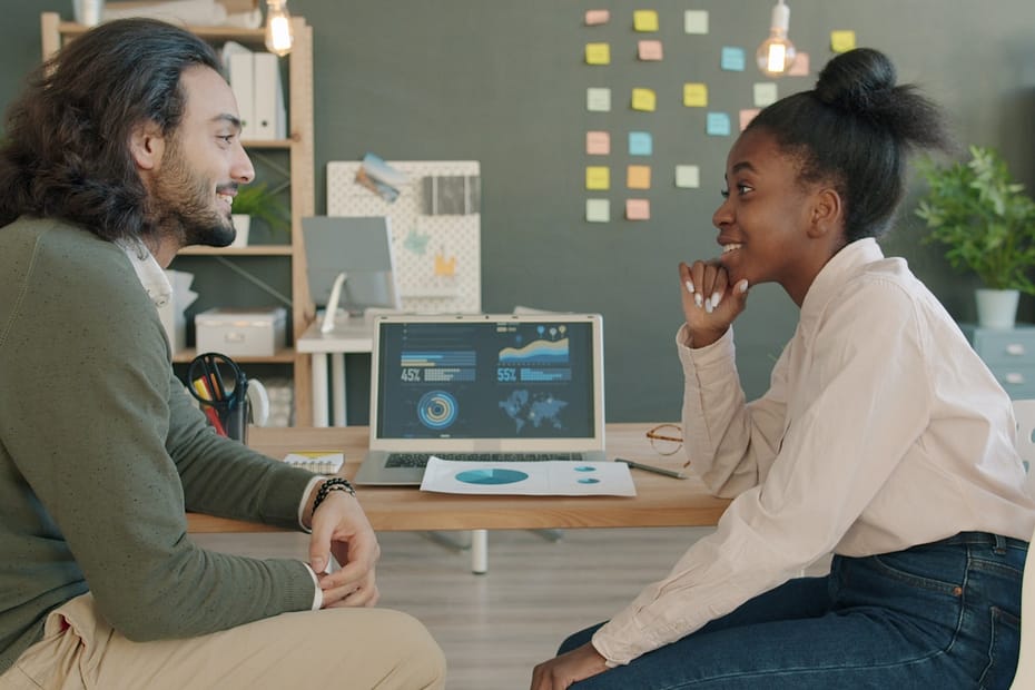 Two colleagues discussing work at a desk.