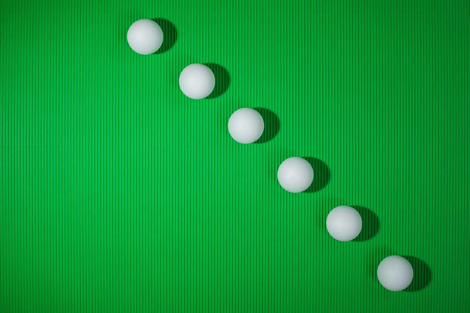 Minimalist design of white balls arranged diagonally on a green textured surface.